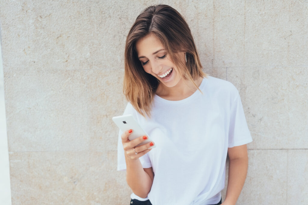 Young woman laughing as she reads a text message